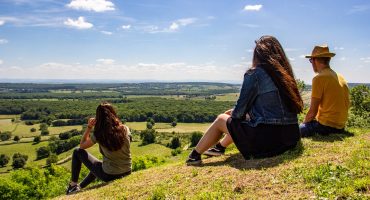 Trois personnes de dos assises sur la butte de Montenoison et qui regardent le paysage